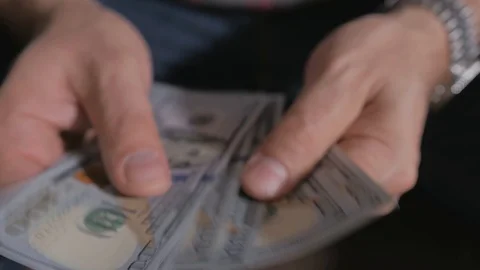 Close-up of a man's hands, counting hundred-dollar bills and putting them in a Stock Footage 120549853