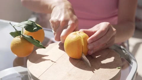 Close-up, a man's hands cut an orange with a knife on a wooden gloss Stock Footage 235125367