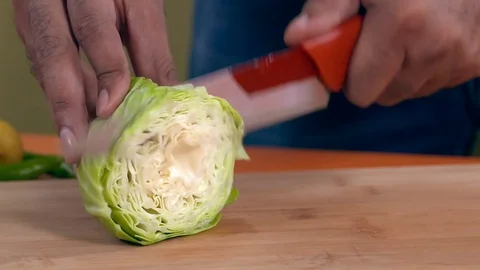 Close up of a man's hands cutting a green cabbage in slow motion in kitchen Stock Footage 112912550