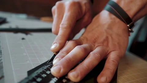 Close-up of a man's hands cutting leather with little knife and line in workshop Stockbeeldmateriaal 146101668