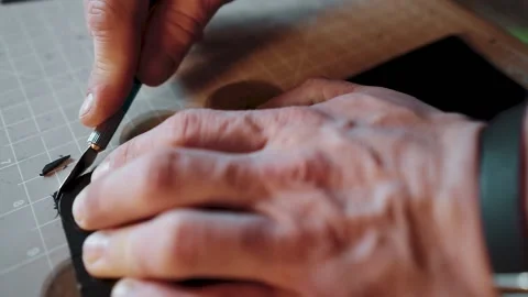 Close-up of a man's hands cutting leather using little knife in workshop Stockbeeldmateriaal 146101682