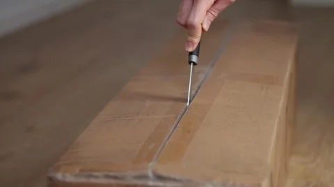 Close-up of a man's hands cutting tape with a knife to open a large box Stock Footage 291889104