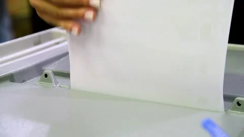 Close-up of a man's hands dropping sheets of paper or a ballot into a votin.. 스톡 동영상 328830098