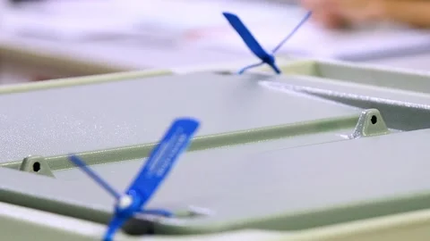 Close-up of a man's hands dropping sheets of paper or a ballot into a votin.. Stockbeeldmateriaal 331205866