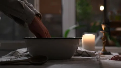 Close-up of man’s hands folding risen dough overflowing from bowl on table. 库存影片 309259484