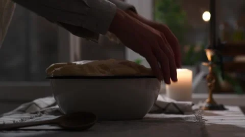 Close-up of man’s hands folding risen dough overflowing from bowl on table. Видео 309259536