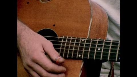 Close-up of man's hands as he plays acoustic guitar, 1970s Stock Footage 90728261