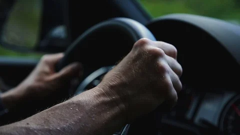 A close-up of a mans hands holding a car steering wheel from the interior of a 스톡 동영상 111448009