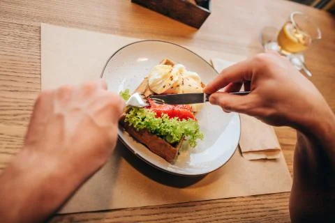 Close up of man's hands holding fork and knofe and cutting dish into two piec Stockfoto's