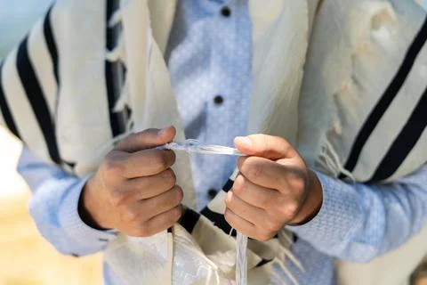 Close-up of a man's hands holding the front tzitzit of his tallit during Shac Stock Photos
