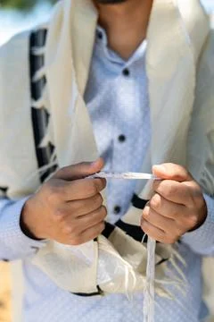Close-up of a man's hands holding the front tzitzit of his tallit during Shac Stock Photos