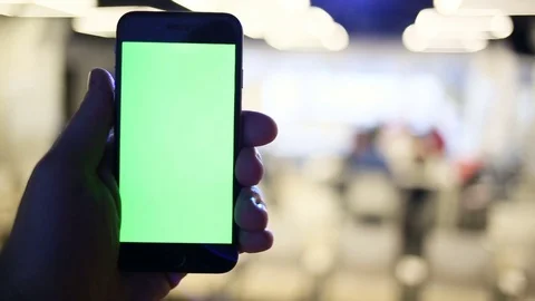 Close-Up of a Man's Hands Holding Green Screen Smartphone a. In the Background Stock Footage 73839846