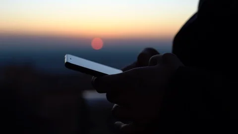 Close-up of man's hands holding mobile phone and browsing internet on sunset Stock Footage 126293801