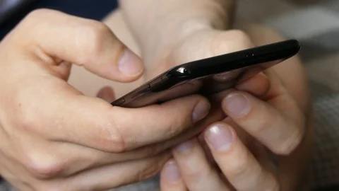 Close up of Mans Hands Holding Modern Smartphone. Man's hands texting on blac Stock Footage