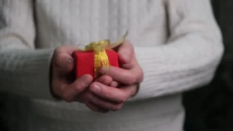 Close-up of a man's hands holding out a red gift box. Gift giving concept. Stock Footage 166503446