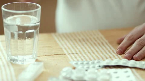 Close Up of Man's Hands Holding Pill and Taking it with Glass of Water 4K 10-bit Stock Footage 332679340