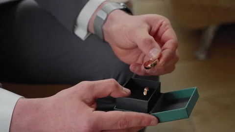 Close-up of Man's Hands Holding Wedding Rings in Elegant Gift Box Vidéo 338352522