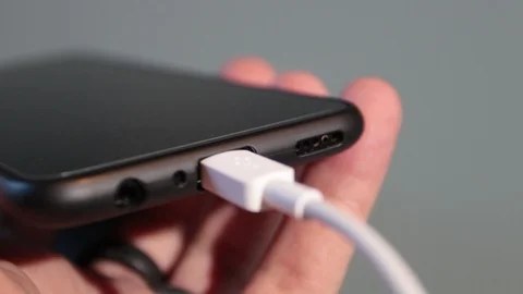 Close up, man's hands inserting the battery charger of a smartphone Stock Footage 120567593