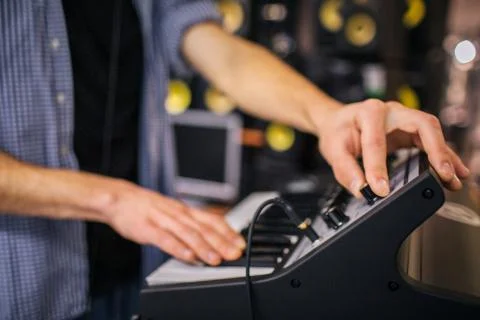 Close up of man's hands on keyboard. Guy turn sound on. He stand in room. Many Stock Photos