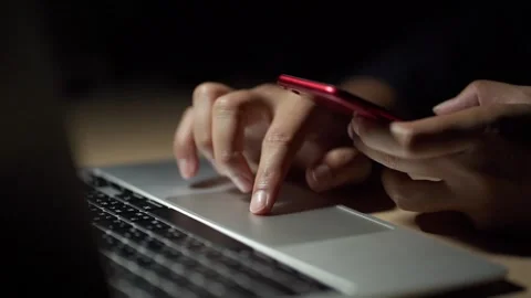 Close up of a man's hands on keyboard of lap top and smartphone in the dark room Stock Footage 254191970