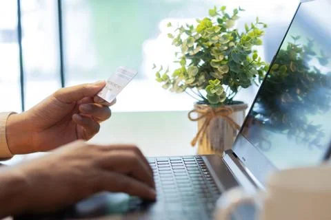 Close up of man's hands with laptop computer and credit card at home. Stock Photos