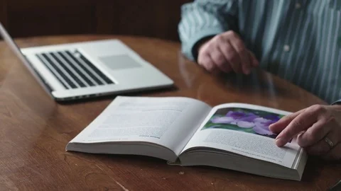 Close up of man's hands making notes from a book on a keyboard Stock Footage 71342131