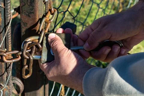 Close-up of a man's hands opening the lock in the gate. Stockfoto's