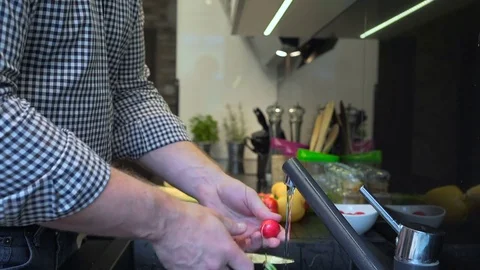 Close up on man's hands peeling and washing radishes. 库存影片 70574333