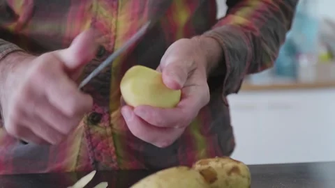 Close Up of Man's Hands Peeling Raw Potato with a Knife in the Kitchen. Stock Footage 322750436