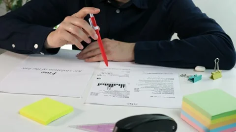 Close up of a mans hands with a pen and a fine in front of him, thinking and Stock Footage 314033944