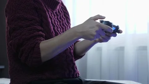 Close-up of man's hands playing video games on game console sitting on sofa 库存影片 334653450