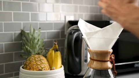 Close-up of a mans hands pouring ground coffee into a drip coffee flask with a Stock Footage 115328504