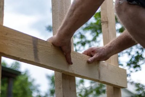 Close-up of man's hands precisely leveling wooden board for construction pr.. Stock Photos