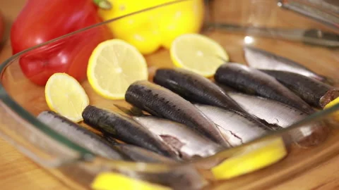Close up man's hands preparing up a baking tray with sardines and lemon. Video stock 143102821