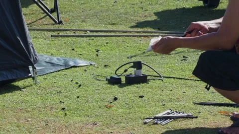 Close-up of a man's hands pulling tent pegs from the grass. Stock Footage 324906464