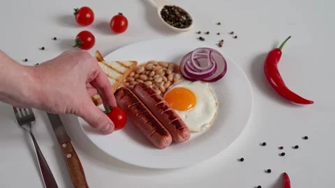 Close-up of man's Hands Puts cherry tomatoes in English Breakfast plate Stock Footage 236249049