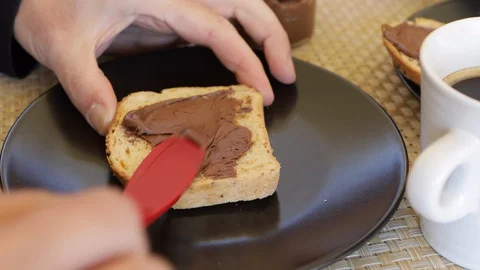 Close up of man's hands that puts chocolate cream on a slice of bread Video stock 128465622