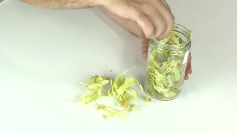 Close-up of a man's hands putting dried herbal tea into a glass jar Video stock 345750271
