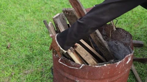 Close up of a man's hands putting a pile of wood into a barrel to make a Stock Footage 339759947