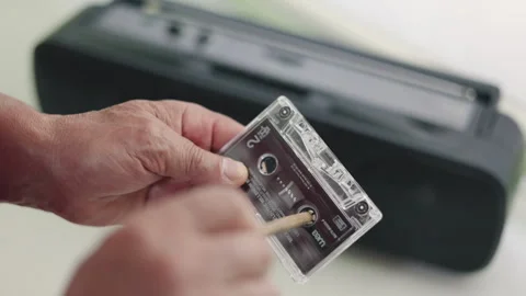 Close up of a man's hands rewinding a vintage audio cassette tape with a pencil Stock Footage 337189594