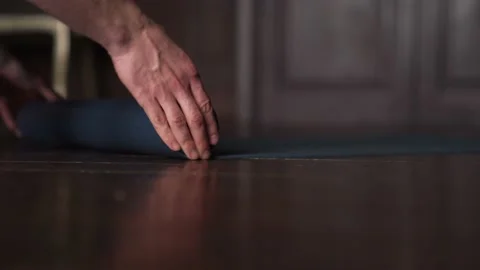 Close Up of Mans Hands Roll Out Yoga Mat For Fitness. Man Rolling Blue Yoga Mat. Stock Footage 152567630