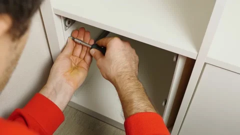 A close-up of a man's hands screwing a self-tapping screw inside a shelf 動画素材 170474648
