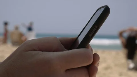 Close up man's hands scrolling mobile phone, sea on the background. Always 스톡 동영상 73714081