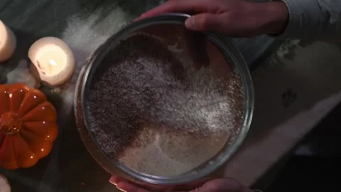 Close-up of man's hands sifting flour to remove husk in low light. Видео 309259313