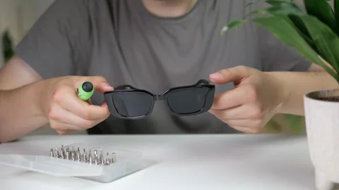 Close-up of a mans hands at a table carefully adjusting a pair of sunglasses Stock Footage 314033861