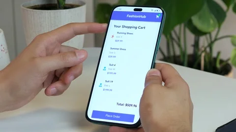 Close-up of a mans hands at a table holding a phone with a shopping cart with an Stock Footage 315290829