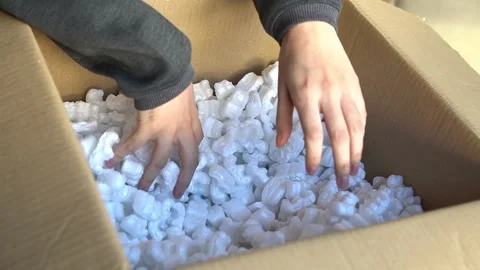 Close-up of a man's hands touching the peanut-shaped cushioning material Stock Footage 296654878