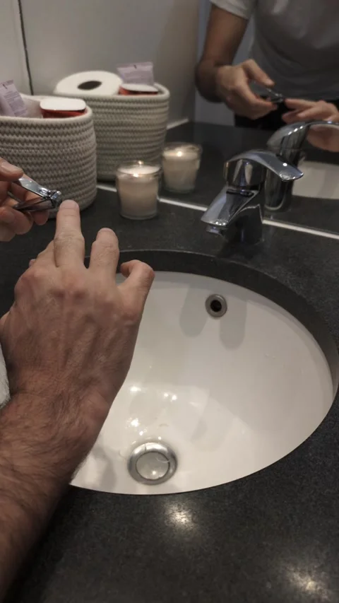 Close-up of man's hands trimming fingernails with nail clipper over sink Video stock 335637441