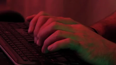 Close up of a man's hands typing on a keyboard with red and green light Stock Footage 118977452