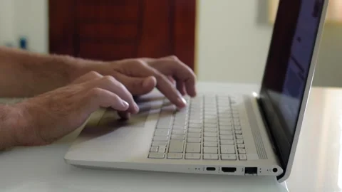Close-up of man's hands typing on a laptop keyboard at a desk in a home office. Vídeo Stock 145465390
